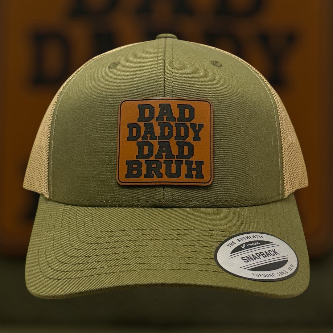 Green cap with 'DAD DADDY DAD BRUH' patch on a blurred background